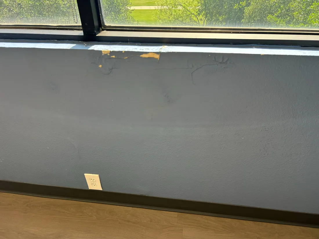 Damaged paint and wall finish below an interior window sill