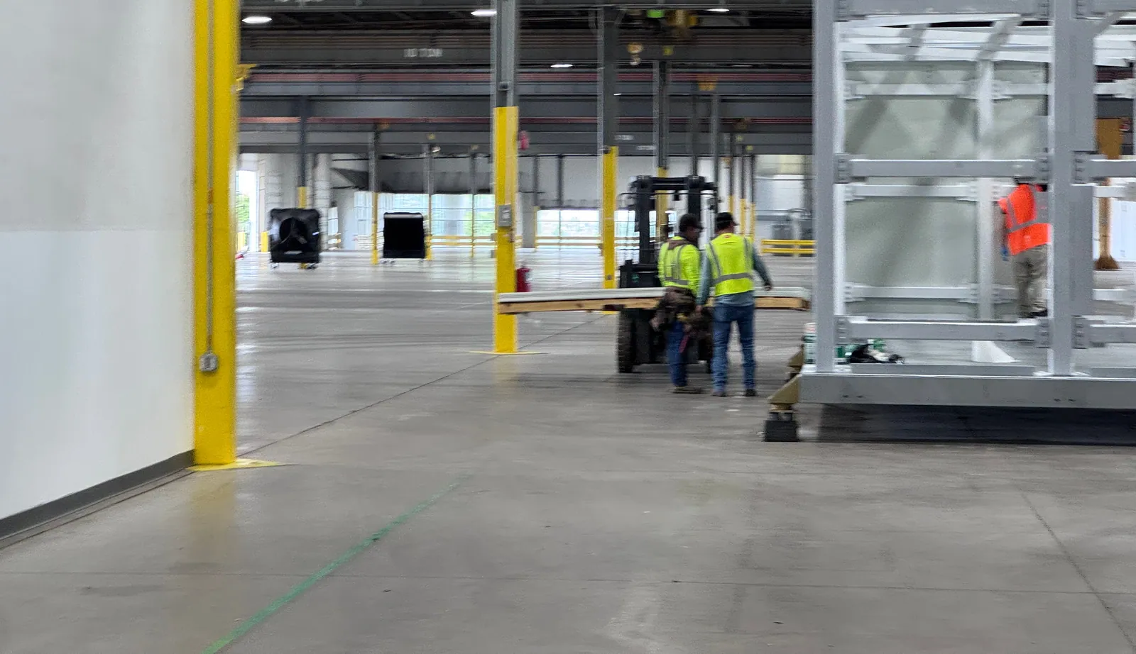 Trades moving materials with a forklift inside a light-industrial building