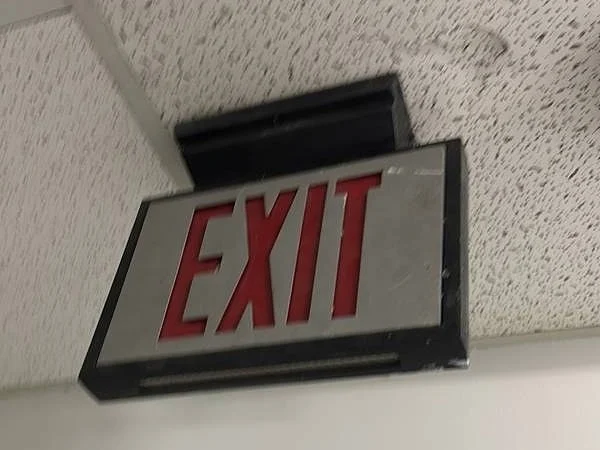 Exit sign mounted at a stairwell ceiling